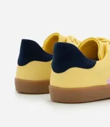 Championes color amarillo con detalles laterales en lila y talón en azul marino.