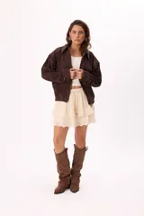 Campera color crema tipo gamuza con cierre frontal, cuello clásico, mangas largas y calados florales en hombros y espalda.