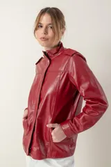 Campera roja de cuero ovino italiano, con charreteras en los hombros, bolsillos laterales, broches ocultos en el frente y broches a la vista en cuello y puños.