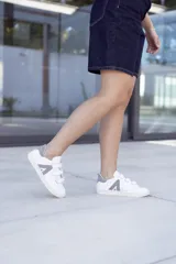 Sneakers blancas con cierre de velcro y diseño minimalista en gris.