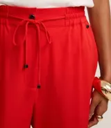 Pantalón femenino de corte fluido, color rojo vibrante, con cintura elástica ajustable mediante lazo y bolsillos laterales.