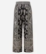 Pantalón largo de corte ancho con estampado paisley en tonos blanco y negro. Presenta cintura alta con trabillas, cierre frontal tradicional y confección en tejido viscolino, una mezcla de lino y viscosa.