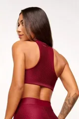 Top deportivo verde con textura tipo panal 3D, cuello alto y estructura firme.