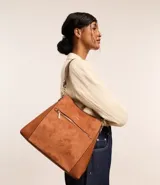 Bolso grande tipo tote confeccionado en PU color marrón, con correa de hombro y bolsillo frontal con cierre.