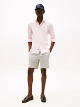 Camisa de popelina rosa claro con tecnología flex, corte slim, cuello abotonado, cierre con botones, logo de Tommy Hilfiger bordado en el pecho y detalles distintivos de la marca.