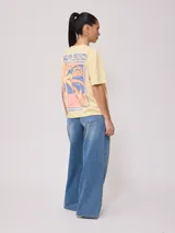 Remera color amarillo claro con estampado en el frente que incluye un sol y el texto 'Rusty Club'. Corte holgado.