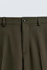 Pantalón de traje color verde oliva oscuro, corte slim fit, con pinzas frontales y bolsillos de doble vivo en la parte trasera.