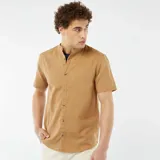 Camisa color beige de manga corta con cuello mao y cierre frontal con botones.