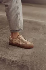 Zapatillas bajas negras con estampado de piel de serpiente metalizada y suela color caramelo.