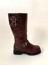 Bota de caña media de cuero vacuno color marrón oscuro, con punta cuadrada, cierre lateral y suela track negra. Presenta detalles de hebillas metálicas plateadas en la caña y en la parte inferior del empeine.
