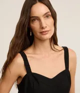 Mono de mujer color rojo oscuro (bordó), de corte recto y pierna ancha, con escote corazón y tirantes anchos con elástico. Presenta pliegues frontales que caen rectos hasta el ruedo.