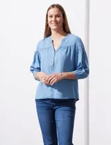Blusa celeste de lyocell con cuello a la base, escote en V con botones y mangas 3/4 con puño abotonado.