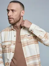 Sobrecamisa beige y marrón a cuadros con dos bolsillos frontales con solapa y cierre abotonado.