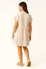 Vestido corto con cuello camisero, de corte holgado y mangas cortas. Presenta un diseño a rayas verticales en tonos beige y blanco, con volados en la falda y cierre frontal con botones.