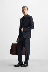 Blazer slim fit azul marino confeccionada en tejido con 17% de lana. Cuello con solapas de muesca, manga larga acabada en puño con detalle de botones, bolsillo de vivo en pecho y de solapa en cadera, detalle bolsillo interior, bajo con aberturas en espalda y cierre frontal con botones.