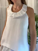 Blusa de lino 100% natural, color blanco, con cuello tableado y silueta recta. Presenta un diseño sin mangas con espalda descubierta y tiras regulables.