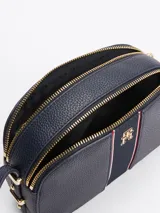 Bandolera ovalada azul marino con correa ajustable, cierre superior con cremallera y logo de la marca en el centro.