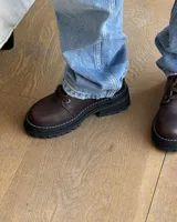 Borcego marrón de cuero con cordones, caña baja y suela track.