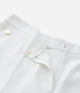 Bermuda de crepé color rojo, con pliegues frontales y botones decorativos en los bolsillos laterales.