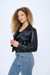 Chaqueta corta estilo motoquera de cuero sintético negro, con cuello solapa y cierre cruzado con cremallera. Decorada con tachas plateadas en solapas, hombros y mangas.