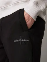 Pantalón de chándal negro de felpa de mezcla de algodón reciclado, con cintura elástica con cordón, puños de canalé, bolsillos con ranura y bolsillo trasero. Presenta un monograma bordado de Calvin Klein en la pierna.