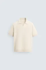 Polo color crema de punto con cuello solapa y abertura frontal en V.