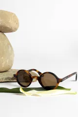 Lentes de sol con montura redonda negra y cristales verdes.