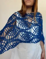 Poncho azul tejido a mano con diseño calado y detalle de mostacillas en el borde.