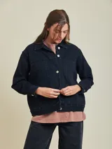 Campera de jean azul oscuro, corte clásico, con cuello camisero, cierre frontal con botones metálicos, bolsillos en el pecho y laterales.