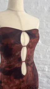 Vestido corto marrón con estampado animal print, corte ajustado, escote strapless con aberturas en el frente y breteles finos.