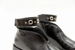 Botín de cuero color borgoña con taco bajo, corte en V en el empeine, pulsera con detalles metálicos y cierre lateral.