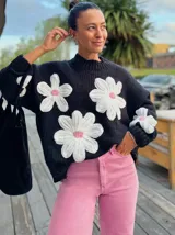 Sweter negro de punto con flores bordadas en blanco y detalles en rosa.