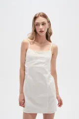 Vestido corto de algodón color blanco, con breteles finos y detalle de broderie bordado en el pecho. Presenta un diseño entallado con frunces laterales y cierre.