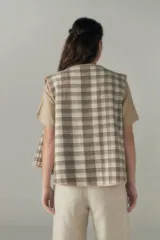 Chaleco marrón con solapas amplias y terminaciones envivadas. Diseño reversible y sin mangas.