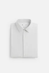 Camisa celeste de corte slim fit, confeccionada en tejido de algodón. Tiene cuello italiano, mangas largas con puños abotonados y cierre frontal con botones.