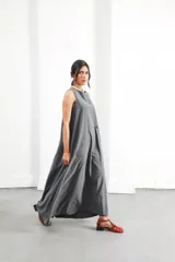 Vestido largo gris sin mangas, con escote redondo, espalda con abertura, bolsillos laterales y logo bordado a contratono en el frente.