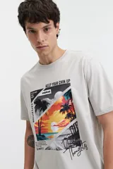 Remera de manga corta color gris claro con cuello redondo y estampado con palmeras, atardecer y texto.