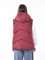 Chaleco puffer color bordó con capucha y bolsillos laterales.