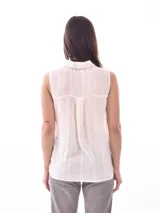 Camisa sin mangas color crudo con cuello clásico, cierre frontal con botones y diseño calado vertical.