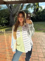 Camisa de manga larga con diseño patchwork a rayas horizontales en tonos celeste, naranja y verde. Tiene cuello clásico, bolsillo en el pecho y cierre con botones.
