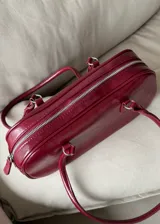 Cartera baguette de cuero sintético color borgoña con doble asa corta.