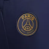 Pantalón de fútbol Nike del Paris Saint-Germain, modelo Strike. Diseño azul marino con detalles en dorado y patrón geométrico en la parte inferior de las piernas.