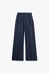 Pantalón de tiro alto color azul denim, con pinzas delanteras, bolsillos frontales, pernera ancha y pespuntes combinados a contraste en color beige.