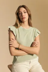 Chaleco tejido sin mangas color verde claro, con cuello redondo y volados en las sisas con terminación en contraste.