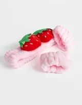 Set de accesorios para el pelo color rosa, compuesto por una vincha con apliques de frutillas y dos muñequeras.