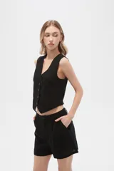 Chaleco negro sin mangas con cuello en V y cierre frontal con botones.