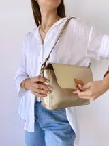 Bandolera dorada de cuero con forro de tela, bolsillo interno, correa larga con cadena desmontable y correa corta de cuero desmontable.