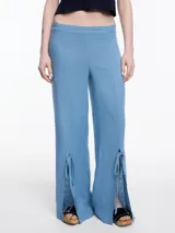 Pantalón ancho celeste de lino y viscosa, con tajos y lazos en la botamanga.