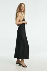 Vestido largo negro de seda, con escote en V pronunciado y tirantes finos que se unen en la espalda con un diseño halter.