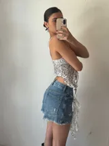 Top plateado con lentejuelas, breteles finos y lazo ajustable en el frente.